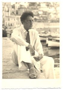 Portrait plein pied assis de Jean Cocteau sur le quai de Villefranche-sur-Mer